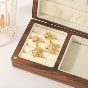 Elegant gold star earrings with sparkling crystals displayed in a wooden jewelry box