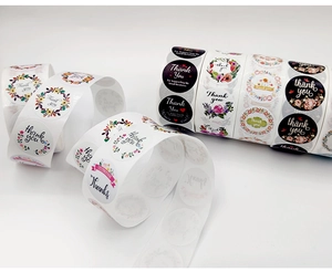 Close-up of multiple rolls of floral Thank You stickers for gift and small business packaging