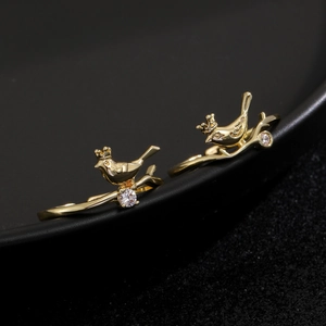 Detailed close-up of vintage golden hummingbird ring with crystal on black background
