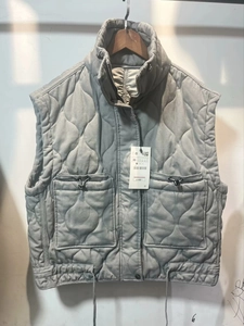 Detail of grey quilted vest featuring a stand collar with zip and snap button closure