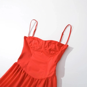 Robe rouge élégante à fines bretelles et buste structuré sur un fond blanc minimaliste