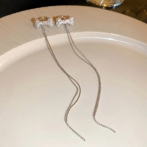 Gros plan de boucles d'oreilles pompon argentées avec design en os serti de diamants