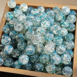 Macro detail of sky blue ice-cracked glass beads for DIY jewelry making in wooden bowl