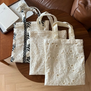 Vintage French lace embroidered handbags in floral patterns on a dark wood table