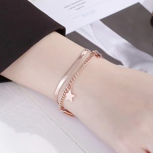 Detail of rose gold double-layer bracelet with star pendant and snake chain texture