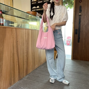 Pink pleated shoulder bag worn by model in a warm cafe setting for a casual summer style