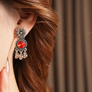 Close-up of vintage silver flower earrings with red gemstone and beaded tassel on a model