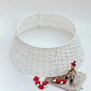 White woven Christmas tree collar base cover with holiday decorations on white background