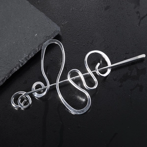 Irregular silver metal hair stick with smooth glossy finish on a dark stone background