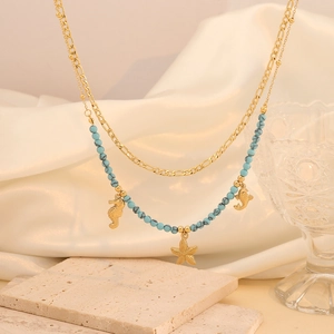 Detail of bohemian layered necklace with gold sea charms and teal marbled beads on satin