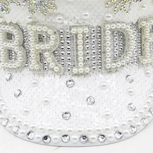 Detailed view of white captain hat with BRIDE pearl lettering and rhinestone accents