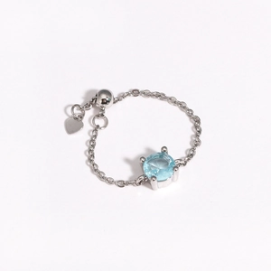 Detail of adjustable silver chain ring with round light blue zircon and heart charm