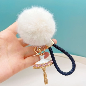 Detailed view of ballet girl keychain with white faux fur pompom and pink rhinestone dress