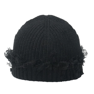 Black distressed knit beanie with fringe edges and retro street style on white background