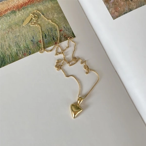 Elegant 925 sterling silver heart necklace with gold finish on an artistic book background