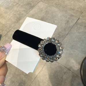 Dettaglio macro del fermaglio in velluto nero con decorazioni floreali di strass brillanti