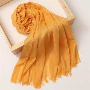 Detail of soft orange linen cotton scarf with frayed tassel edges in a wooden frame