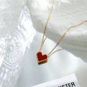 Collier en chaîne dorée élégant avec pendentif cœur rouge et bord perlé sur fond blanc