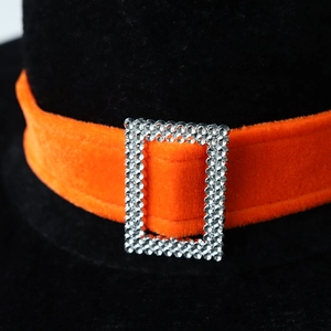 Macro detail of velvet witch hat with orange velvet strap and rhinestone buckle