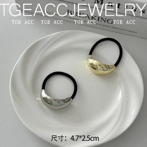 Detail of gold and silver geometric metal hair ties on a white ceramic plate