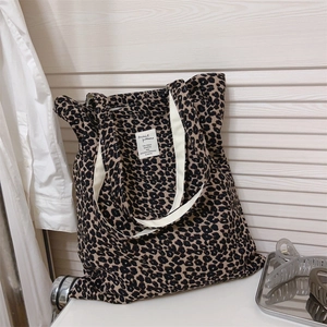 Detailed view of leopard print canvas tote bag with woven brand label and thick straps