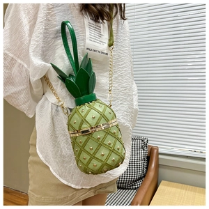 Close-up of green pineapple shaped crossbody bag with metallic rivets and leaf handle detail