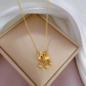 Detailed view of a gold Fu character longevity lock necklace with bells in a jewelry box