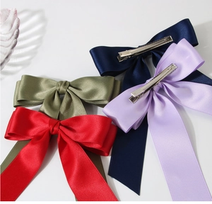 Close-up of four silk satin bow hair clips in navy, purple, olive, and red with metal grips