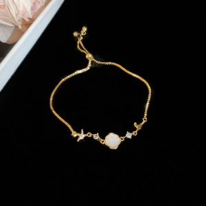 Detail of adjustable gold bracelet with shell flower, starfish and zircon charms