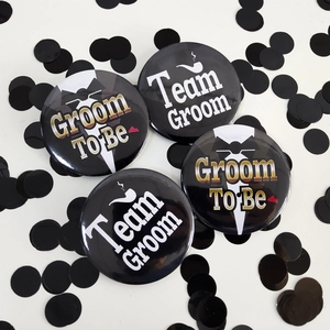Vista piatta delle spille Groom To Be e Team Groom con eleganti paillettes nere