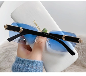 Detail of rimless gradient blue sunglasses with gold arrow accents and leather case