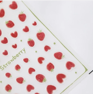 Macro detail of 3D textured summer strawberry and heart pattern nail stickers for kids.