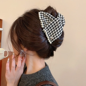 Detail of houndstooth fabric hair claw with pearl trim worn on back of head