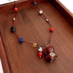 Retro beaded necklace with wood horse pendant and gold coin accent on a dark wood tray