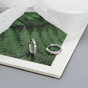 Macro shot of silver S925 geometric hoop earrings with sparkling cubic zirconia on a card