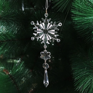 Sparkling transparent acrylic snowflake pendant hanging on a green Christmas tree branch