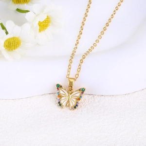 Detailed macro view of gold butterfly pendant with white enamel and colorful gemstones