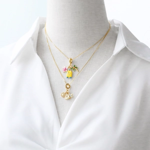 Gold layered necklace featuring colorful travel pendants on a white mannequin display