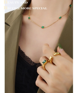 Detail of 18K gold necklace and ring set featuring rectangular emerald green zircons