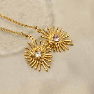 Détail des colliers cœur rayonnant avec zircons roses et blancs sur finition dorée