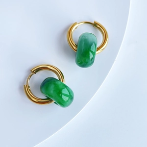 Detail of 18k gold plated hoop earrings with green natural stone charms on white tray
