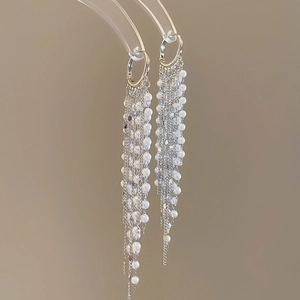 Detail of silver long tassel earrings with pearls and shiny sequins in light luxury style