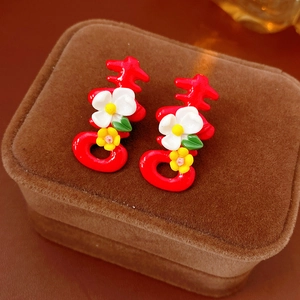Detailed macro view of red Double Happiness earrings with flowers on velvet jewelry box