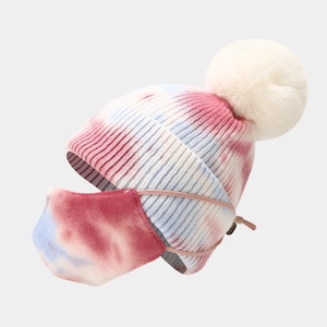 Dettaglio del berretto in maglia tie-dye per bambini con pompon in pelliccia e mascherina