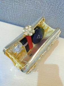 Detail of gold evening clutch bag showing floral rhinestone clasp and interior lining