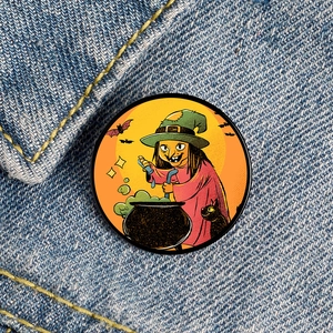 Detail of Halloween witch and black cat badge pinned on blue denim fabric texture