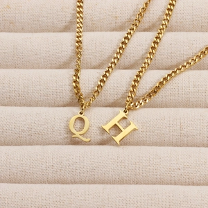 Detailed close-up of 18K gold plated letter Q and H pendants on Cuban chains