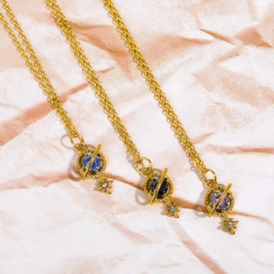 Detail of vintage 18K gold Saturn necklaces with blue, black, and purple gemstones