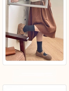 Detail of dark grey ribbed crew socks paired with brown shearling Mary Jane shoes on wood