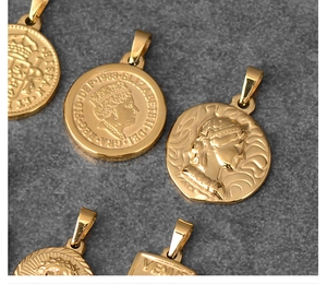 Detailed view of 18K gold plated coin pendants with Roman portraits on stone surface